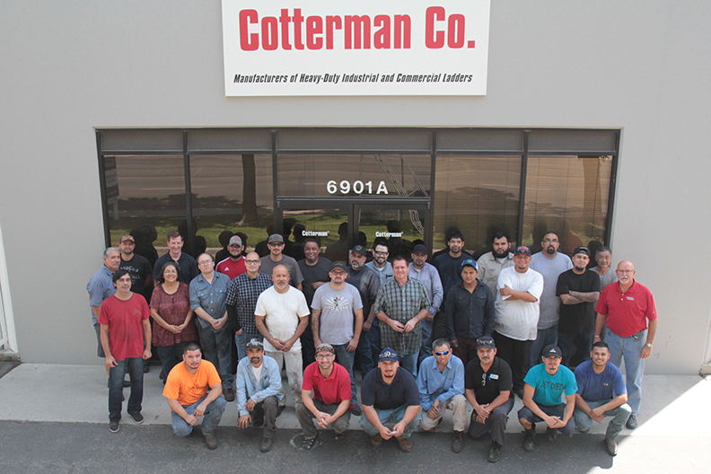 Cotterman staff stand smiling outside of the Cotterman Co. office and sign.
